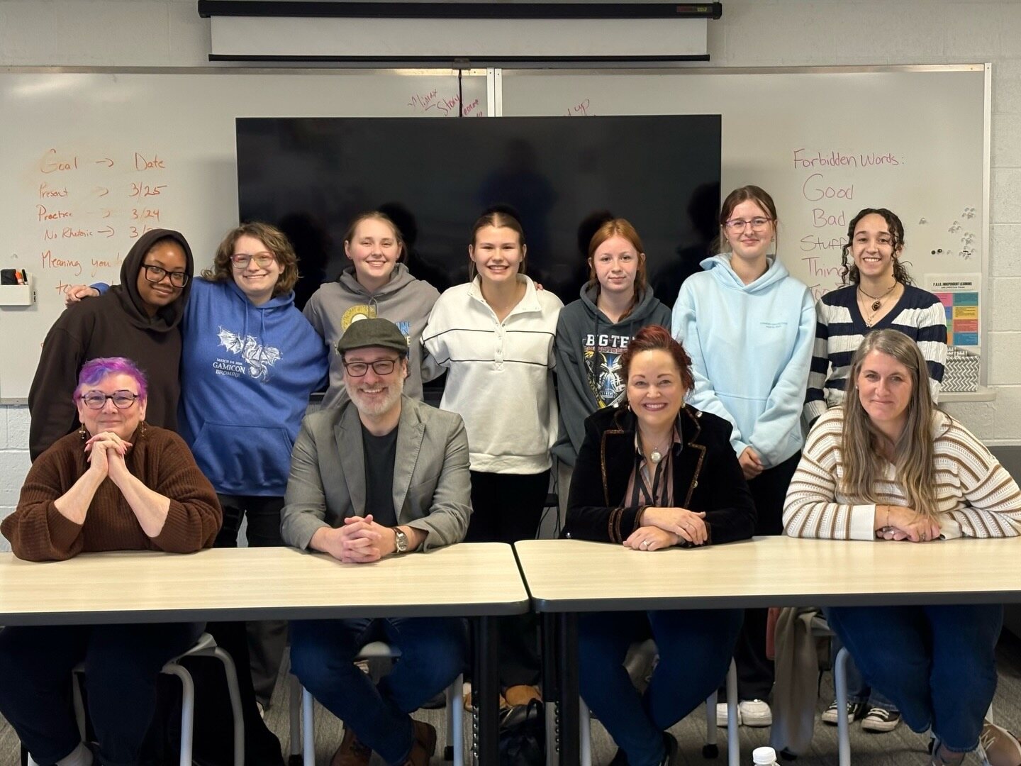 Craig A. Hart seated with students during a Cedar Rapids high school author visit