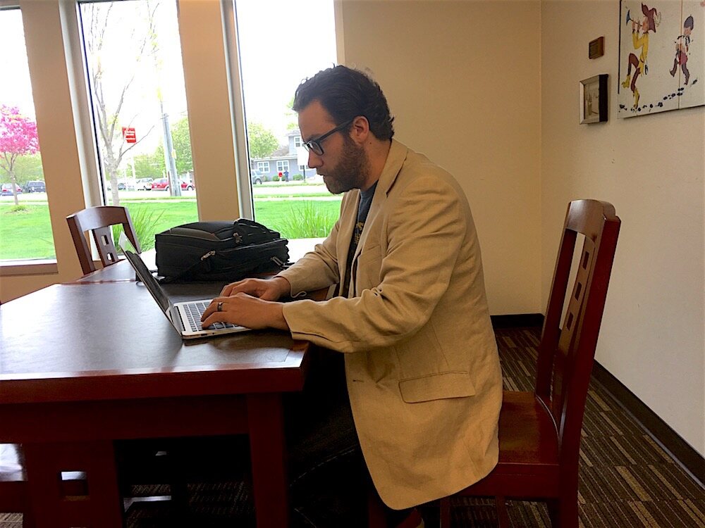 Craig A. Hart working on a laptop at a library table